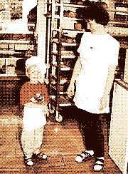 A young Thomas in a baker's hat and apron, smiling next to his mother in the back of his parents' bakery.